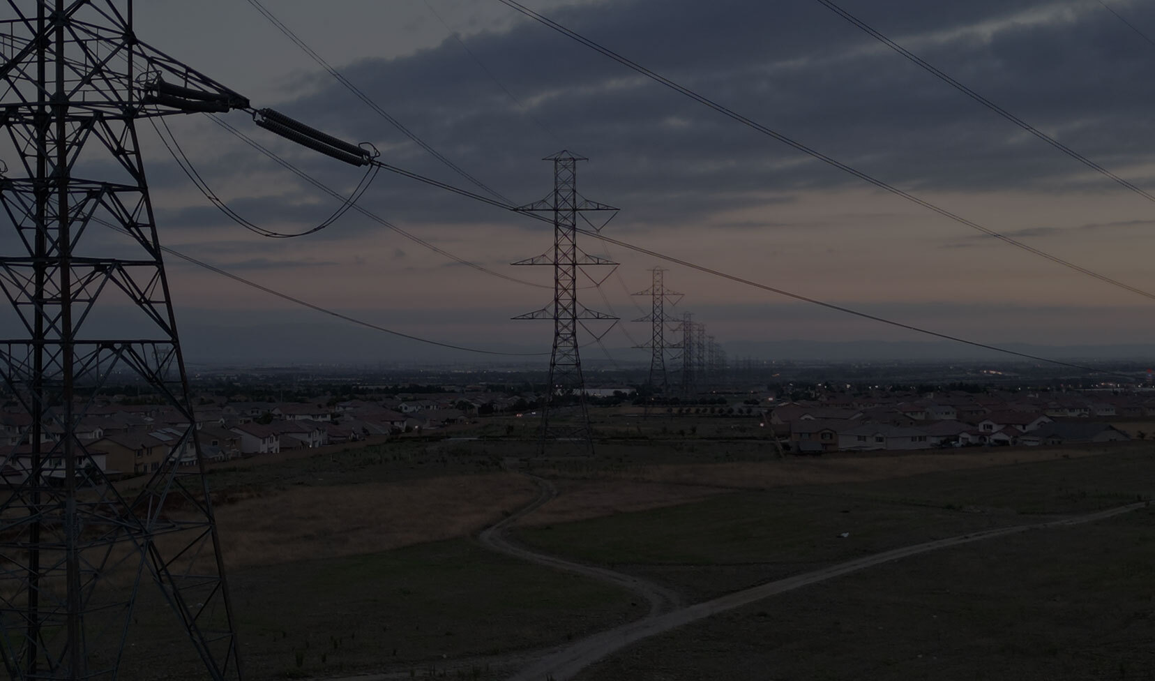 Aerial view of transmission power lines running near homes in city, showing utility infrastructure in a fire-prone region.